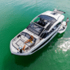 Aerial view of a Galeon 435 GTO yacht with its sliding sunroofs fully open, showing people relaxing on the spacious bow sunpads while another person stands on the extended swim platform over calm green water.