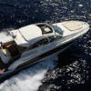 Aerial view of a Prestige 440S yacht cruising at speed with a partially opened ATC sliding sunroof, featuring a foredeck sunpad, teak swim platform, and a passenger seated in the open cockpit.