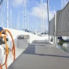Excess 11 Catamaran helm station with steering wheel and Raymarine instruments, gas spring fitted under the bench seat for easy lifting, marina view in background